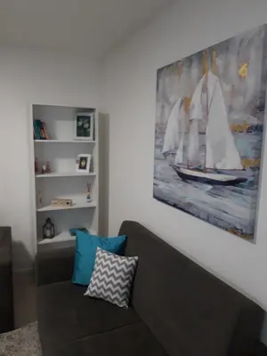 a living room with a couch and a painting of a sailboat at Elena apartmani Tuzla in Tuzla