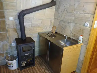 a wood stove in a kitchen with a sink at Apartmani i sobe 