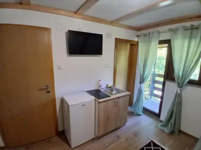 a kitchen with a sink and a television on the wall at Apartmani i sobe 