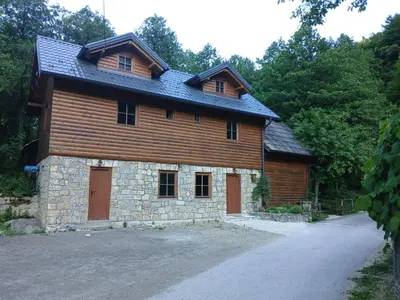 a large wooden house with a gambrel roof at Apartmani i sobe 