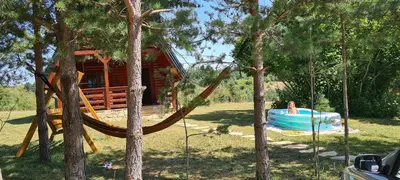 a woman in a hammock in front of a cabin at Ranč Crna stina in Livno