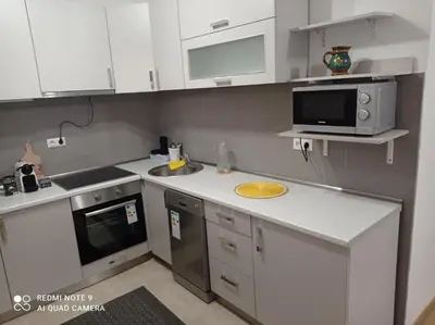 a kitchen with white cabinets and a sink and a microwave at DALMAR Apartman in Bihać