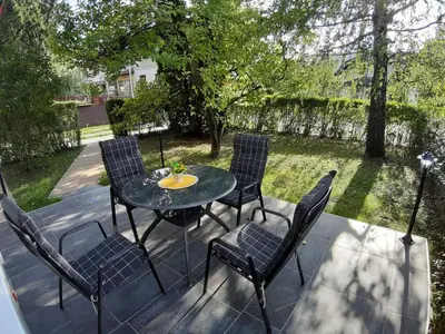 a patio with a table and chairs on a deck at DALMAR Apartman in Bihać