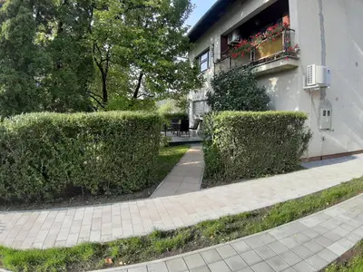 a building with hedges in front of a sidewalk at DALMAR Apartman in Bihać