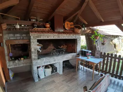 an outdoor kitchen with a stone fireplace on a deck at DALMAR Apartman in Bihać