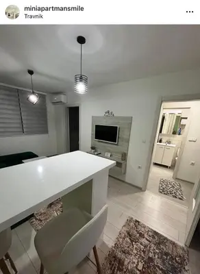 a kitchen with a white counter and a living room at Mini apartman Smile Travnik in Travnik