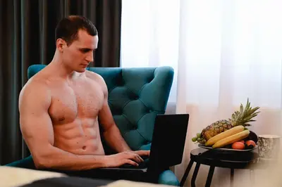 a shirtless man sitting in a chair using a laptop at Spa Intimo Doboj in Doboj