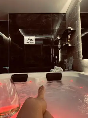 a person laying in a bath tub with a glass of wine at Spa Intimo Doboj in Doboj