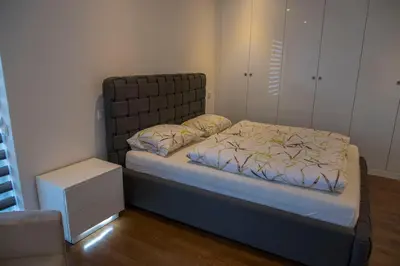 a bedroom with a bed and a night stand at Penthouse Linnet Bihać in Bihać