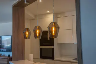 four lights hanging from a mirror in a kitchen at Penthouse Linnet Bihać in Bihać