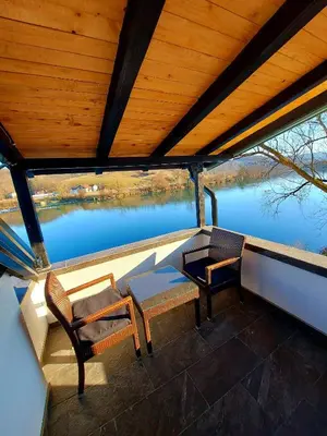 two chairs and a table on a balcony with a view of water at Apartments Marshal in Bosanska Krupa