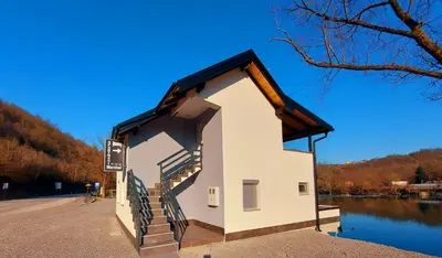 a small building with stairs next to a body of water at Apartments Marshal in Bosanska Krupa