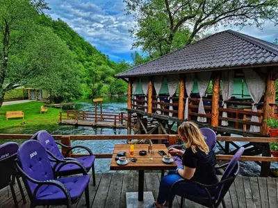 a woman sitting at a table in front of a cabin at Apartments Marshal in Bosanska Krupa