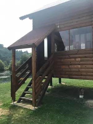 a cabin with a wooden roof on the grass at Vikendica Na Plivi in Šipovo