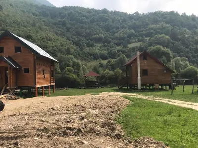 two wooden barns in front of a mountain at Vikendica Na Plivi in Šipovo