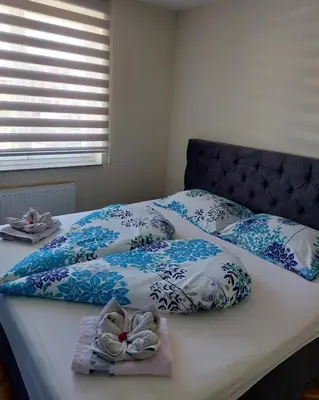 a bed with blue and white blankets and pillows on it at LNB Lux in Doboj