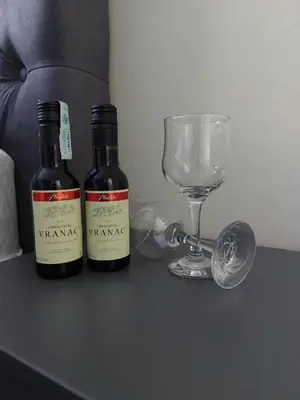 two bottles of wine and a wine glass on a table at LNB Lux in Doboj