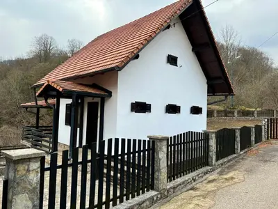 a small white house with a black fence at Vikendica Mlinovi in Krupa na Vrbasu