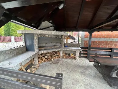 a stone fireplace in a patio with a wooden bench at Vikendica Mlinovi in Krupa na Vrbasu