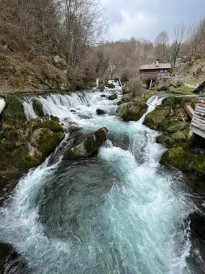 a river with water rushing over rocks next to a building at Vikendica Mlinovi in Krupa na Vrbasu