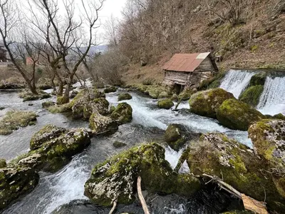 a small cabin next to a river with a waterfall at Vikendica Mlinovi in Krupa na Vrbasu