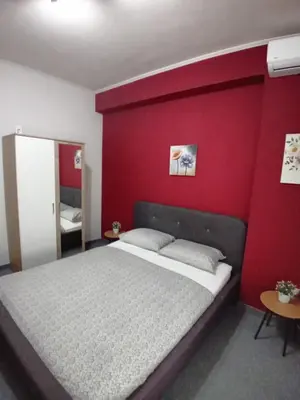 a bedroom with a bed with a red wall at Pansion San in Bihać