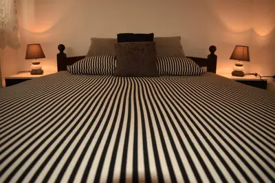 a bed with black and white striped sheets and two lamps at Apartman Archive Jevrejska in Banja Luka