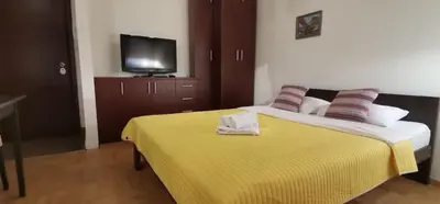 a bedroom with a bed with a yellow blanket and a tv at Apartman Benz studio in Banja Luka