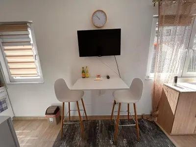 a room with a table and two chairs and a clock on the wall at City apartment 2 in Visoko