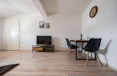 a living room with a table and chairs and a clock at Apartman Luca in Livno