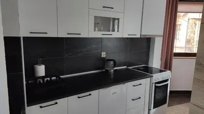 a kitchen with white cabinets and a black counter top at NETWORK apartment in Jajce