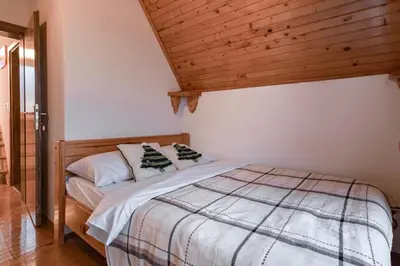 a bed in a bedroom with a wooden ceiling at Villa Ela in Kupres