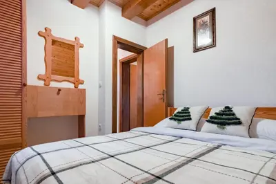 a bedroom with a white bed with christmas tree pillows at Villa Ela in Kupres