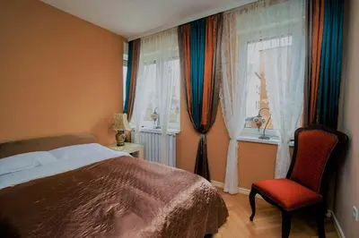 a bedroom with a bed and a chair and windows at Elegant Visoko in Visoko
