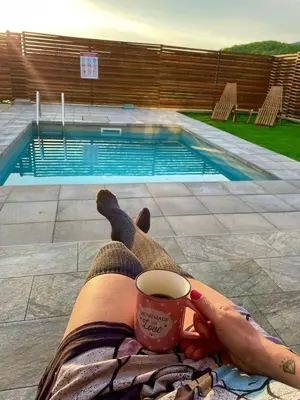 a person holding a cup of coffee next to a swimming pool at Villa Dream House Bihac in Bihać