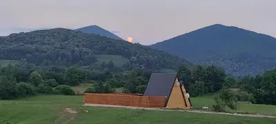 a small house in a field with mountains in the background at Villa Dream House Bihac in Bihać