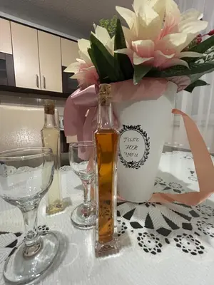 a table with glasses and a bottle and a vase with flowers at Apartman Bošnjak Ramsko jezero in Podbor