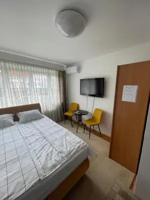 a bedroom with a bed and two chairs and a tv at Studio Apartman Centar in Zenica