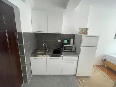 a small kitchen with white cabinets and a microwave at Studio Apartman Centar in Zenica