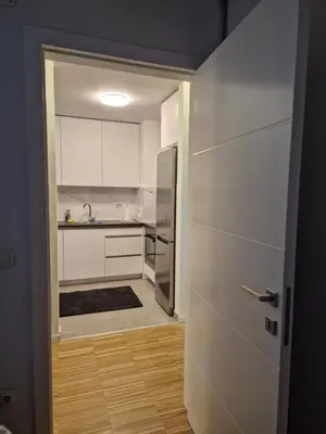 a kitchen with white cabinets and a door leading into a room at Nika in Banja Luka