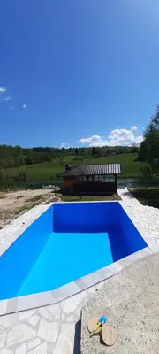 a blue swimming pool with a building in the background at Smjestaj na selu Stankovic - Pliva in Šipovo