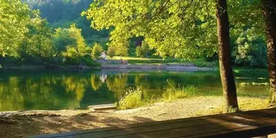 a view of a lake with trees and a bench at Flora&Fauna in Bihać