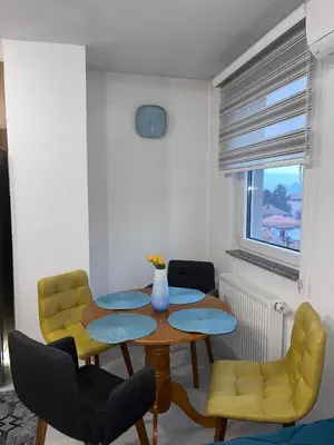a dining room with a table and yellow chairs at Sunset Delux Apartment in Visoko