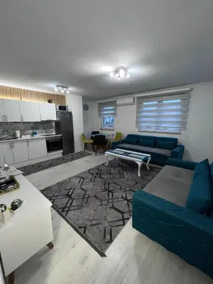 a living room with a blue couch and a kitchen at Sunset Delux Apartment in Visoko