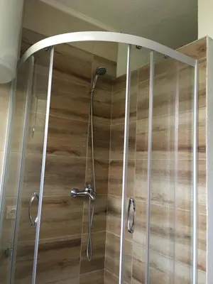 a shower in a bathroom with a wooden wall at Royal Residence in Visoko