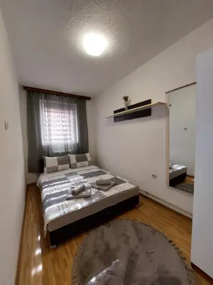 a bedroom with a large bed and a mirror at Apartment EM in Tuzla