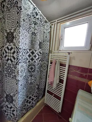 a bathroom with a shower curtain and a window at Apartment EM in Tuzla