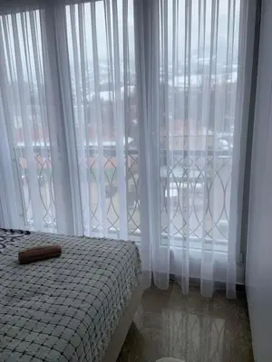 a bedroom with white curtains and a bed and a window at Apartment Aria in Travnik