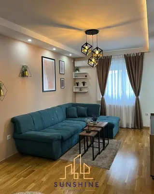 a living room with a blue couch and a table at Apartman Sunshine in Doboj