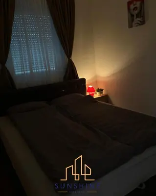 a bed with a black comforter and a window at Apartman Sunshine in Doboj